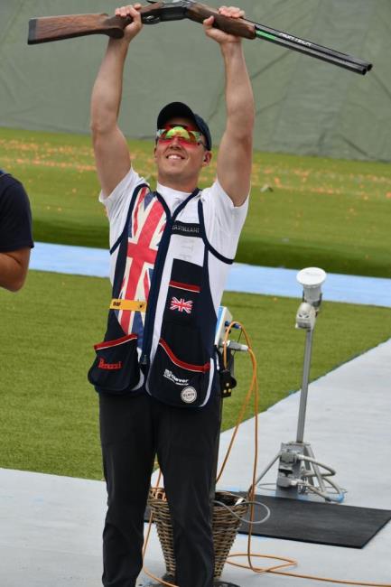 Proudly raises his gun aloft Proudly raises his gun aloft